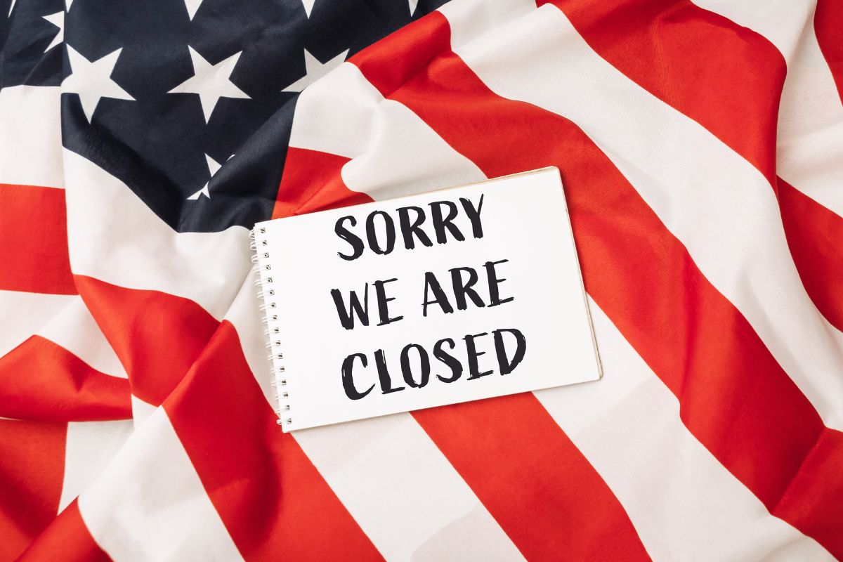 American Flag with a paper saying sorry we are closed