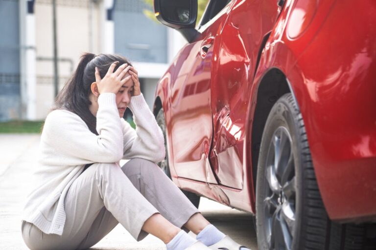 Woman on the road looking at her dented car