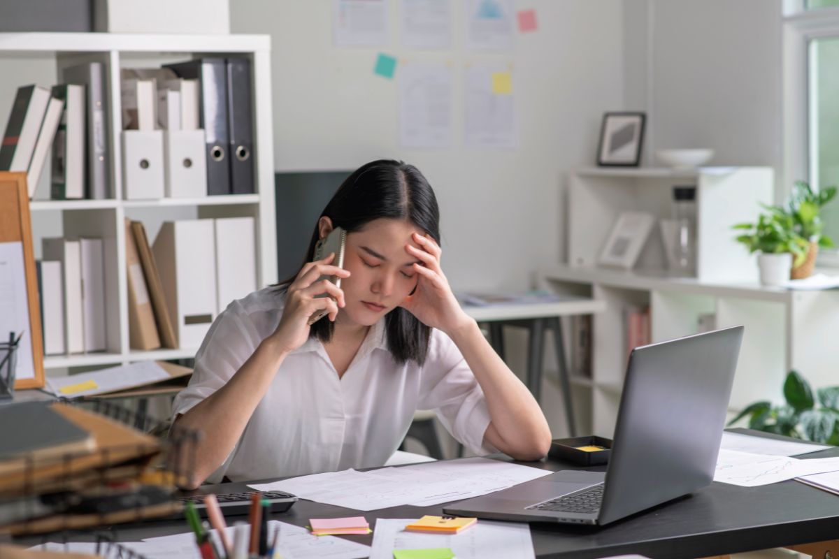 Woman working at a desk on the phone eyes closed thinking