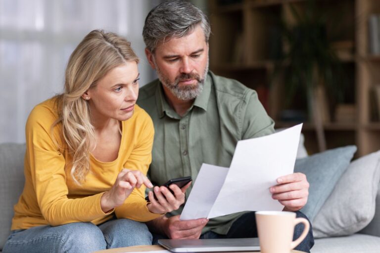 man and woman looking at bills woman holding a calculator