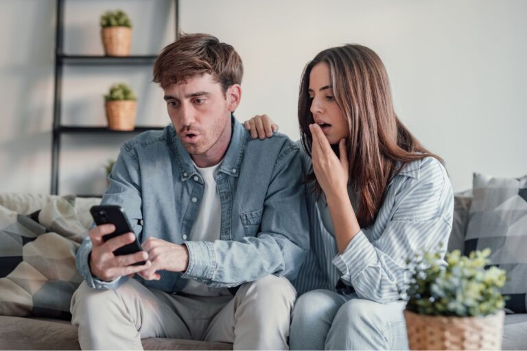 man and woman looking at their phones shocked