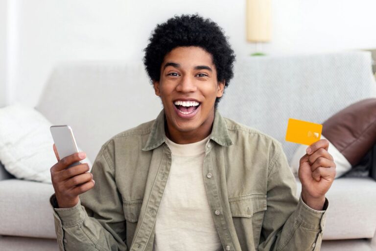 man excited holding his phone and a card in each hand