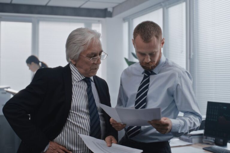 two men looking at a report in an office