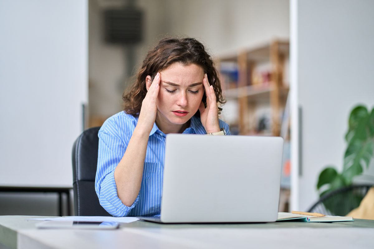woman holding her temples watching the computer