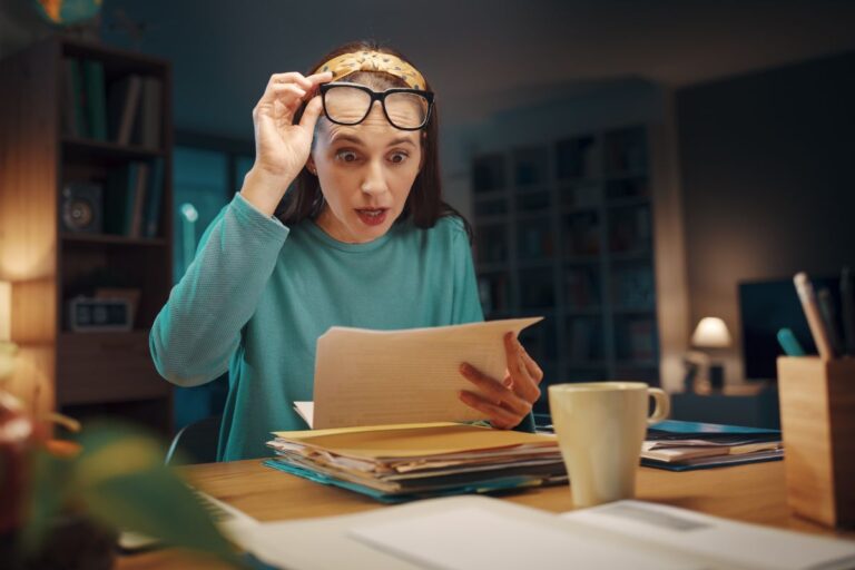 woman looking shocked looking at paperwork