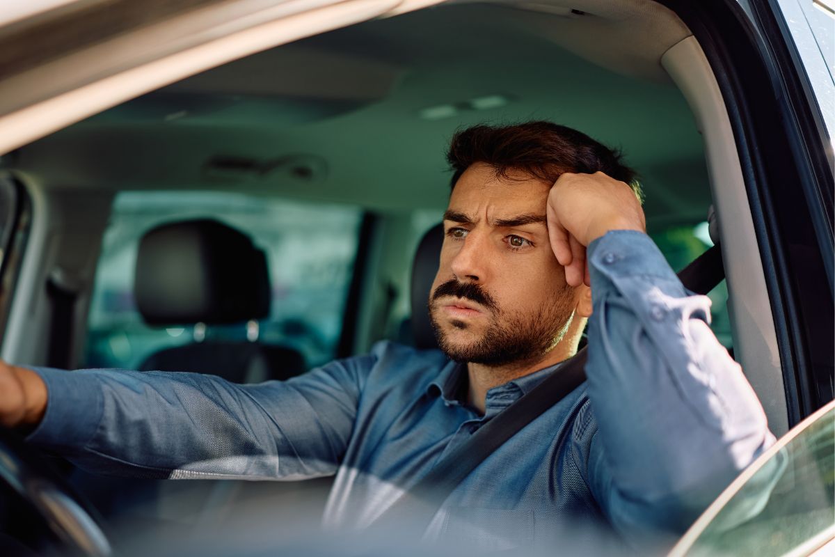 man driving to work hand on his head as if stuck in traffic