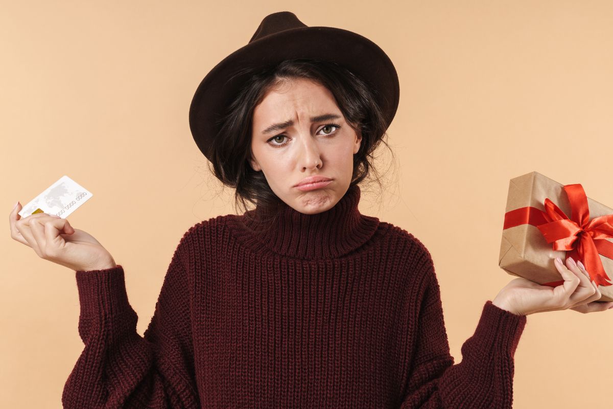 woman holding a gift box and gift card looking dissapointed