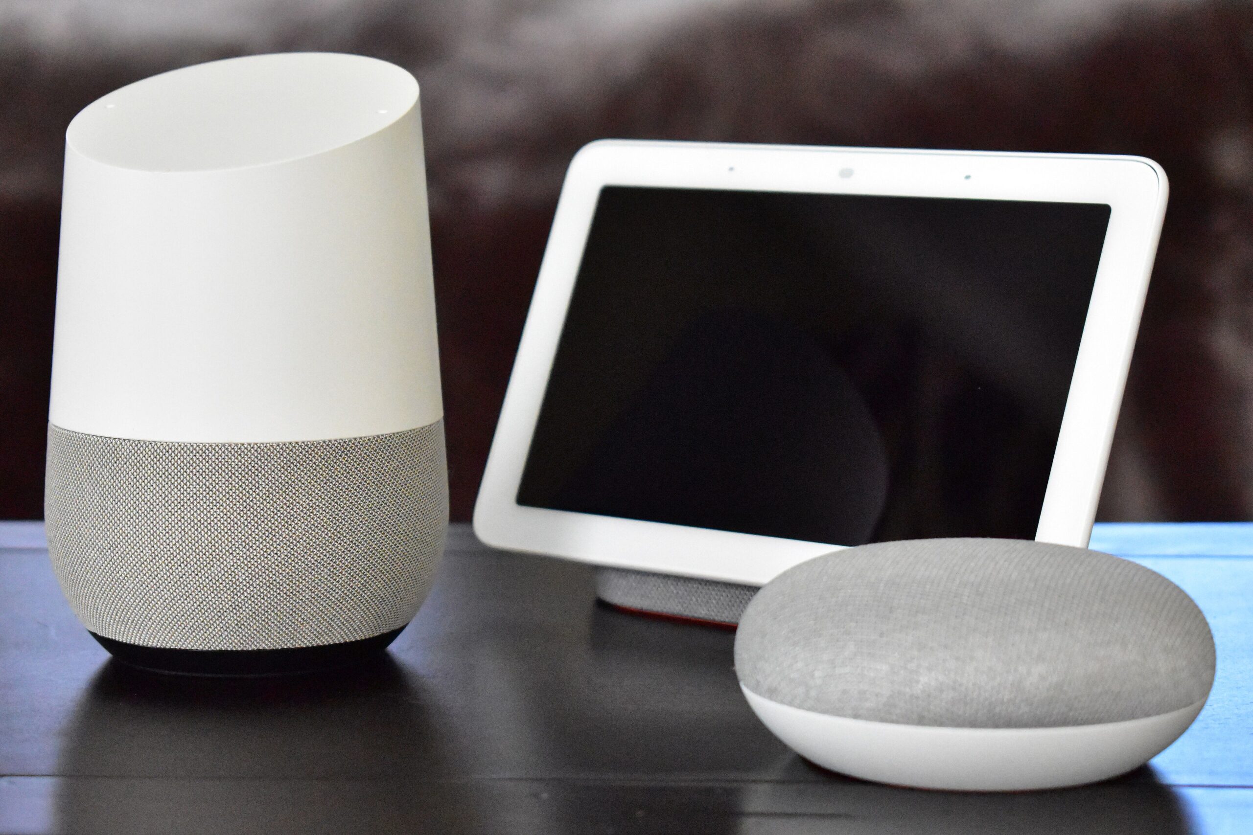A Google Home speaker, Home Hub display and Home Mini speaker sitting on a table