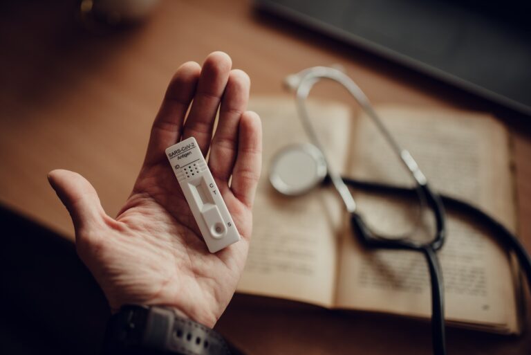 A stethoscope and an open book on a wooden desk in morning light