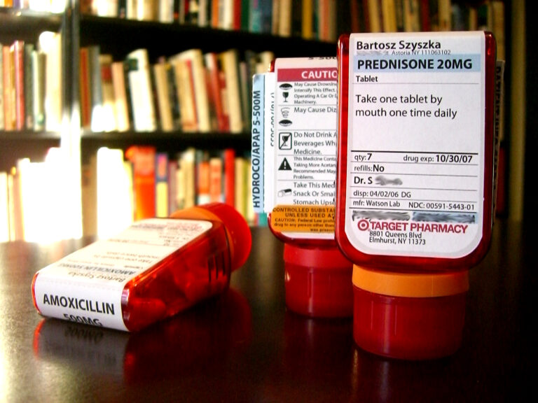 Red prescription pill bottles with pharmacy labels lined up on a counter